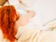 Faut-il vraiment dormir du côté gauche, comme le suggèrent certaines études ? femme rousse qui dort du coté gauche